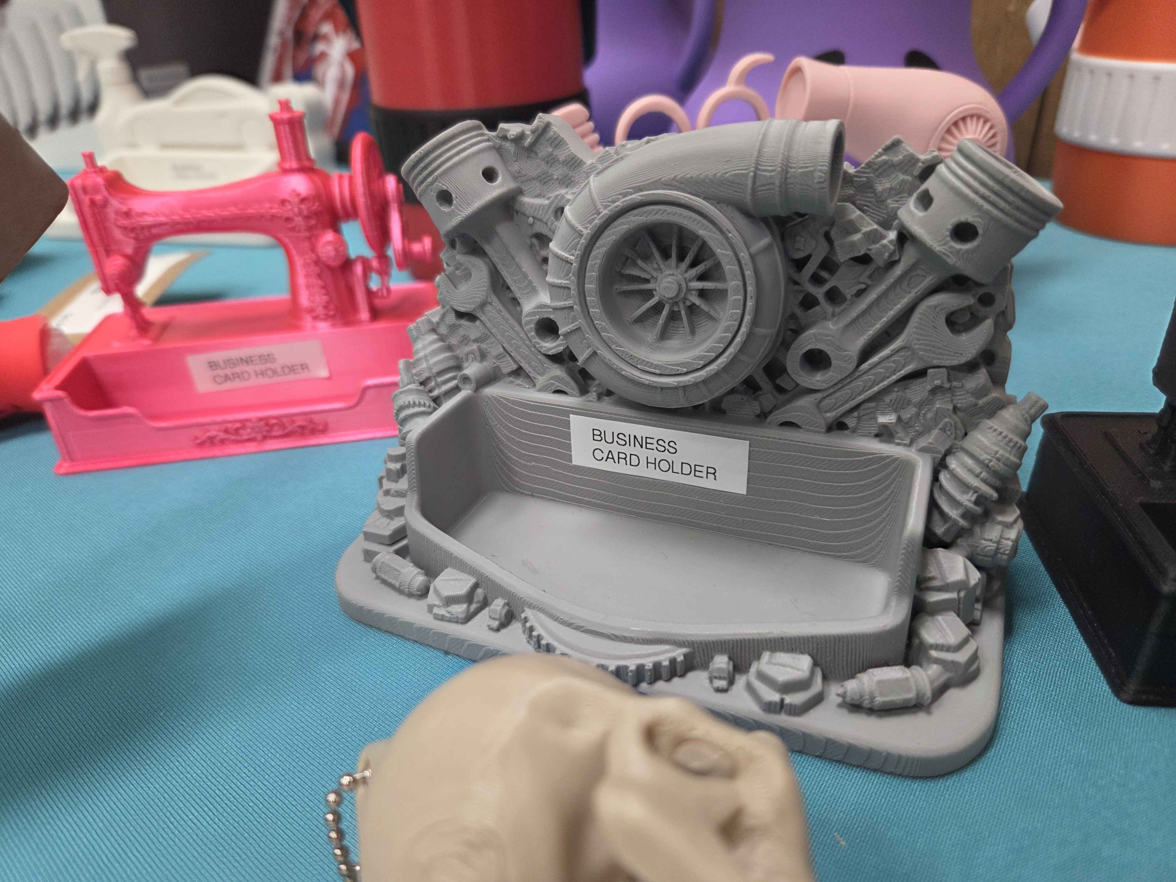 3D printed business card holder designed around mechanic work with a sewing themed business card holder in the background